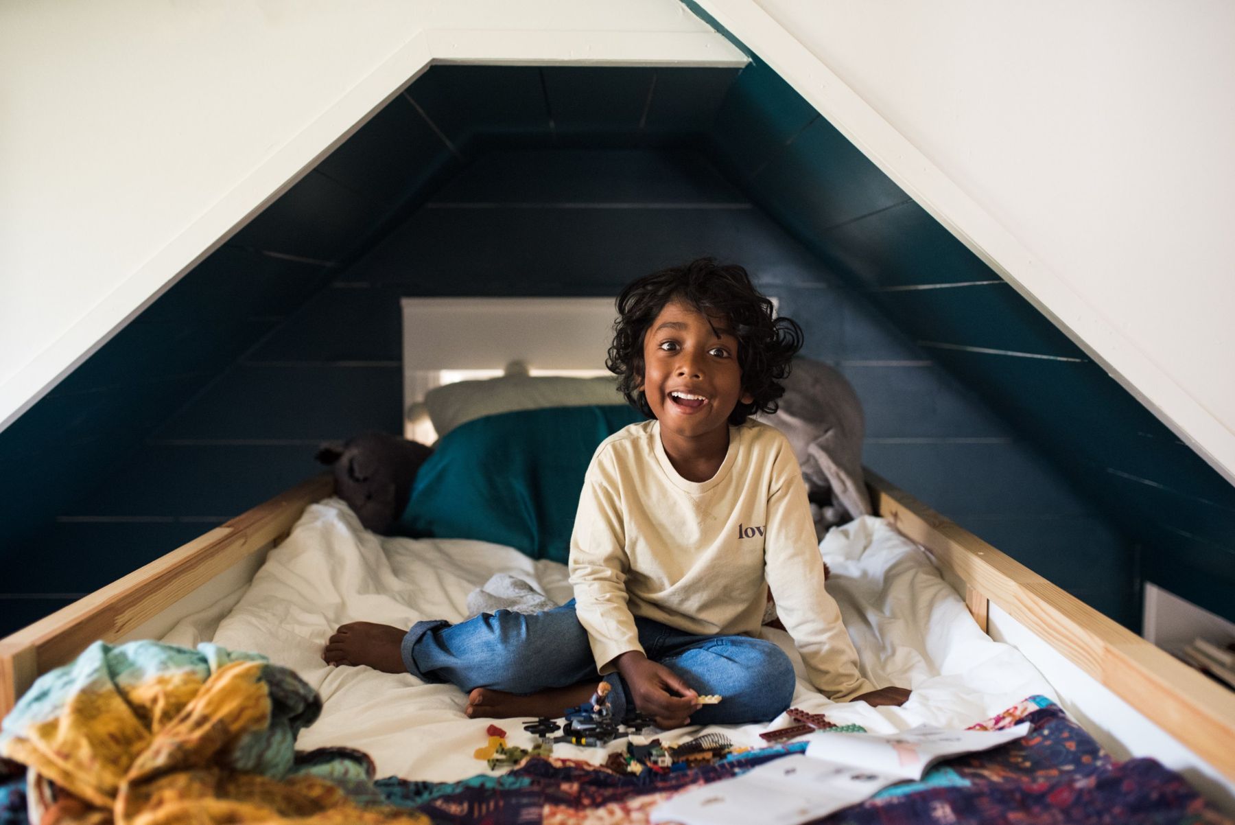 A child grinning in the teal attic nook bed