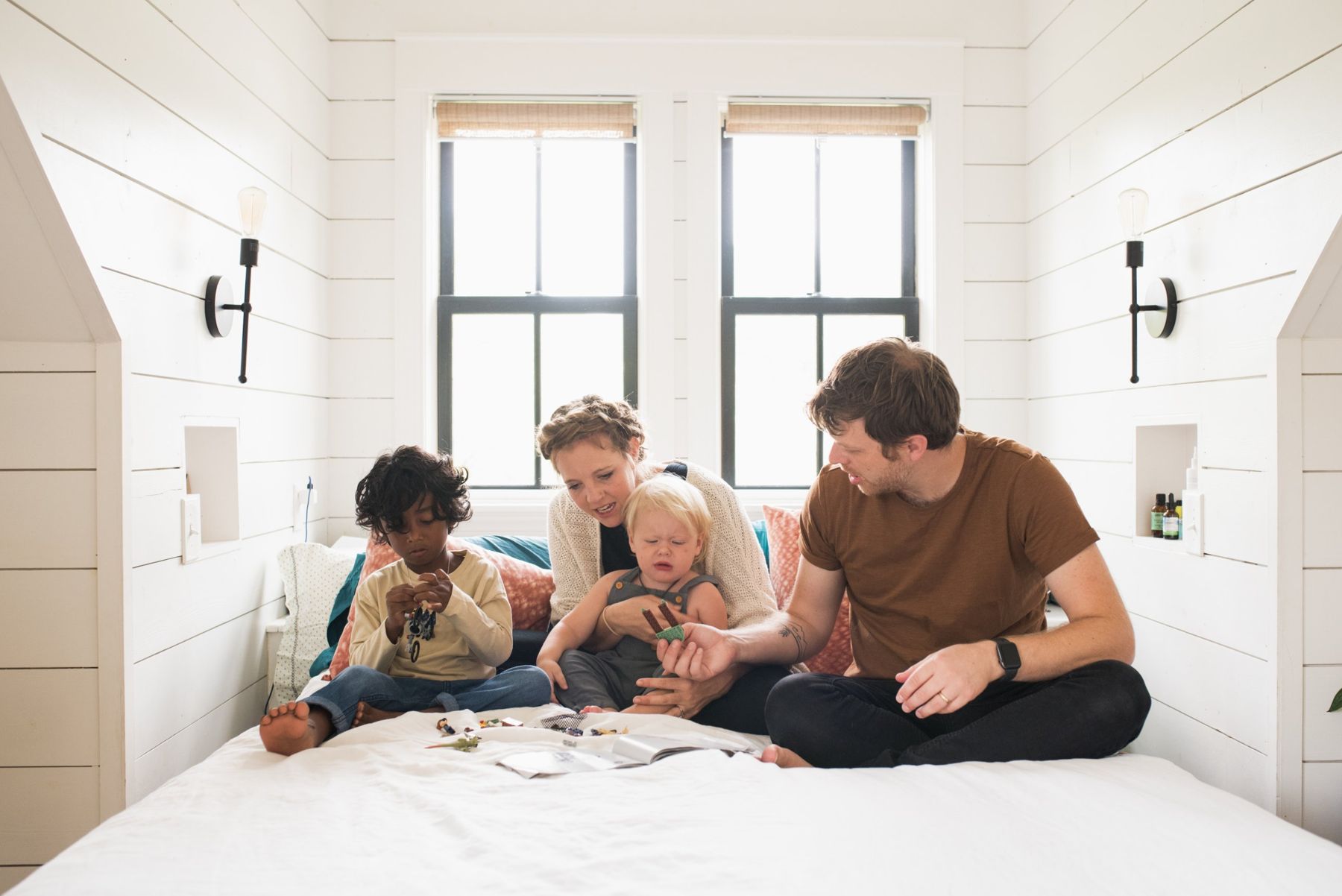 The Kirkegaard family playing with building blocks on a bed in the white shiplap attic bedroom