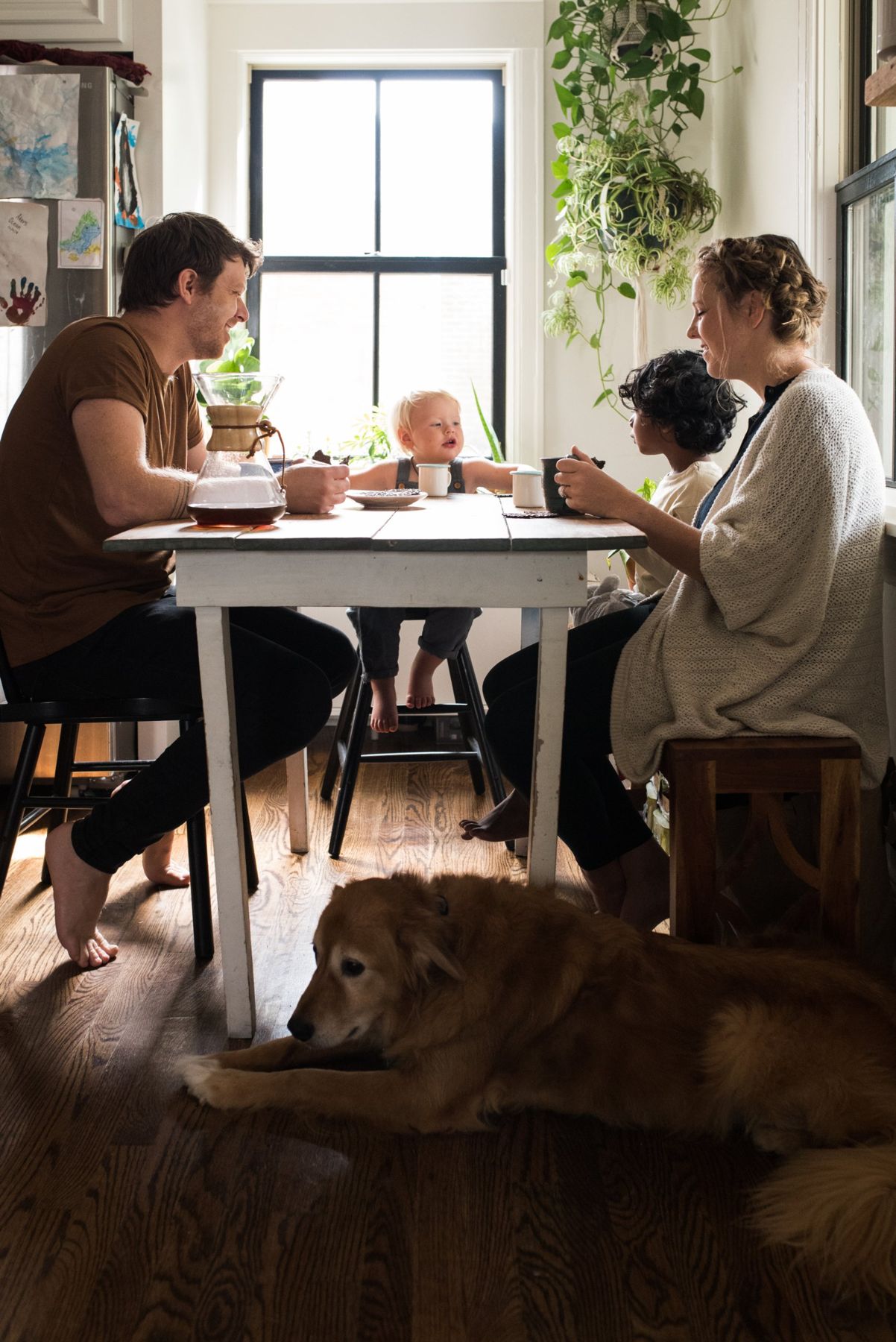 The family at the kitchen table with coffee, the dog stretched out on the wood floor